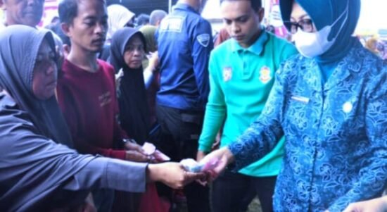 Ketua TP. PKK Provinsi Gorontalo, Gamaria Purnamawari Monoarfa (kanan), turut melayani warga yang berbelanja pada pasar murah di lapangan Kelurahan Padebuolo, Kecamatan Kota Timur.