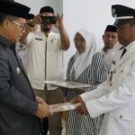 Bupati Gorontalo Utara Thariq Modanggu saat menyerahkan SK Pelantikan Kepada kepala Desa Helumo