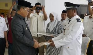 Bupati Gorontalo Utara Thariq Modanggu saat menyerahkan SK Pelantikan Kepada kepala Desa Helumo