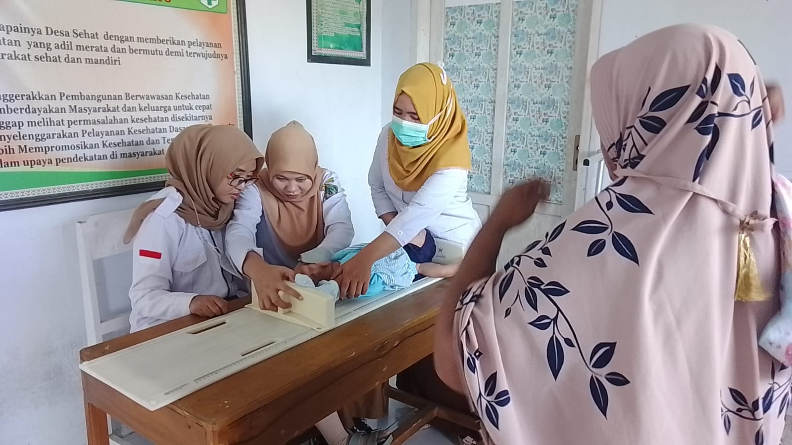 Nakes Puskesmas Berlian saat melakukan pengukuran tinggi badan bayi balita di Desa Diloato