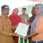 Pj Bupati Boalemo Sherman Moridu saat menyerahkan sertifikat tanah kepada salah satu masyarakat di kecamatan Paguyaman Pantai