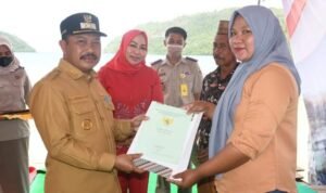 Pj Bupati Boalemo Sherman Moridu saat menyerahkan sertifikat tanah kepada salah satu masyarakat di kecamatan Paguyaman Pantai