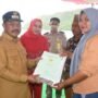 Pj Bupati Boalemo Sherman Moridu saat menyerahkan sertifikat tanah kepada salah satu masyarakat di kecamatan Paguyaman Pantai