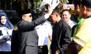 Penjagub Ismail Pakaya memakaikan helm bantuan dari Dinas Perhubungan Provinsi Gorontalo kepada pengemudi ojek daring pada upacara Harhubnas di halaman kantor Bupati Bone Bolango, Senin (18/9/2023).