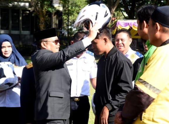 Penjagub Ismail Pakaya memakaikan helm bantuan dari Dinas Perhubungan Provinsi Gorontalo kepada pengemudi ojek daring pada upacara Harhubnas di halaman kantor Bupati Bone Bolango, Senin (18/9/2023).