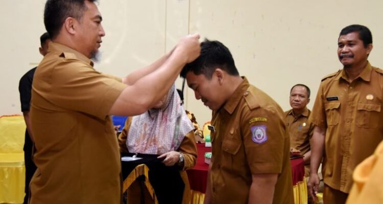 Penjabat Sekdaprov Gorontalo, Budiyanto Sidiki, menyematkan tanda peserta pelatihan penulisan karya tulis ilmiah bagi guru SMA, SMK, dan SLB di aula BPSDM, Selasa (10/10/2023)