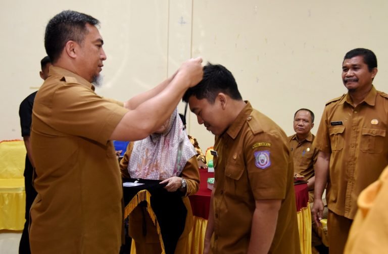 Penjabat Sekdaprov Gorontalo, Budiyanto Sidiki, menyematkan tanda peserta pelatihan penulisan karya tulis ilmiah bagi guru SMA, SMK, dan SLB di aula BPSDM, Selasa (10/10/2023)