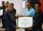 Wakil Bupati Bone Bolango, Risman Tolingguhu serahkan piagam penghargaan kepada Kepala Desa Ombulo Hijau atas capaian terbaik II Updating Data Kemiskinan. (Foto Prokopim).