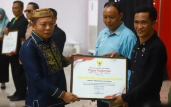 Wakil Bupati Bone Bolango, Risman Tolingguhu serahkan piagam penghargaan kepada Kepala Desa Ombulo Hijau atas capaian terbaik II Updating Data Kemiskinan. (Foto Prokopim).